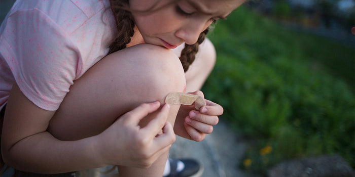 close up of girl putting a bandaid on her knee