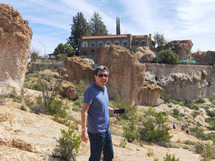 Dr. Pete standing among huge boulders and green shrubs.
