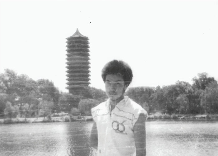 A creased black and white photo of Dr. Pete standing in front of The Nameless Lake on Beijing University's Campus.