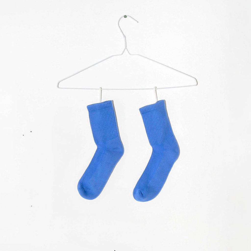 Bright blue socks rest below a wire hanger on a white background.