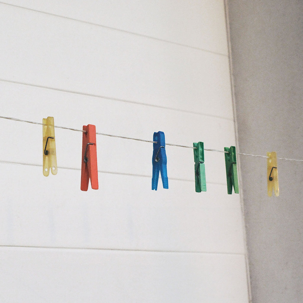 Colorful clothespins hang from a line.