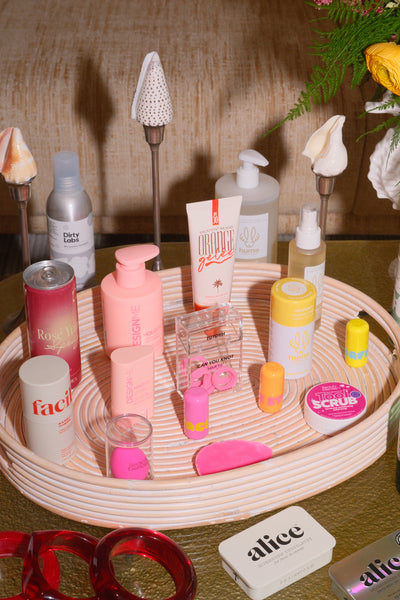 Collection of beauty products on a woven tray with a blurred background