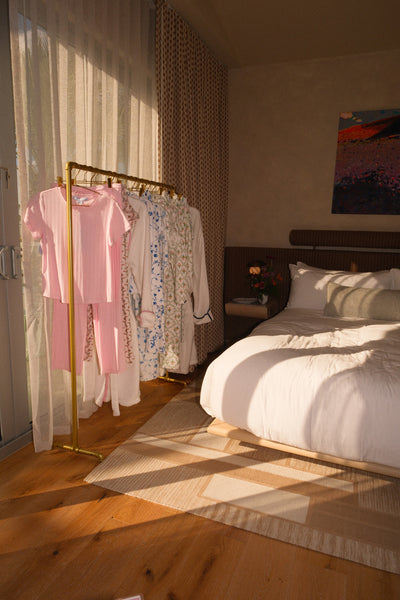 Room with a bed and clothes rack against a wall