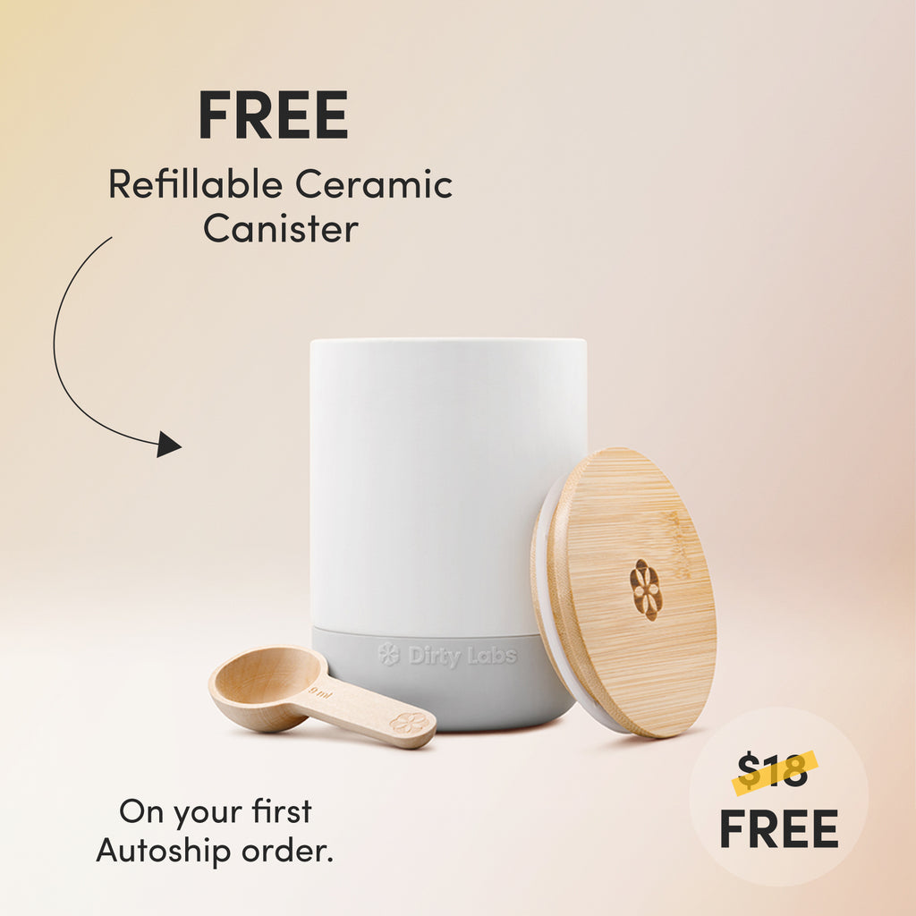 A modern, minimalist ceramic canister is positioned against a light yellow and orange gradient background. A branded bamboo lid and a small wooden scoop sit on either side of the canister. The text around the product reads: "Free Refillable Ceramic Canister. On your first Autoship order.