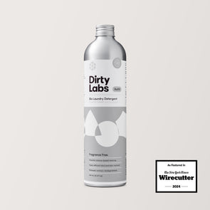 A hand holds an 80-load bottle of Free & Clear Bio Laundry Detergent. The presentation is displayed against a neutral light grey background.