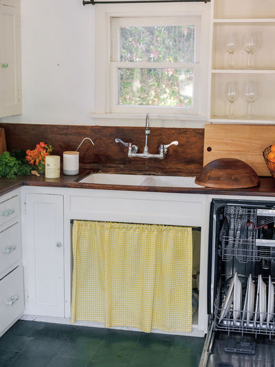 Kitchen with a yellow checkered curtain over a dishwasher