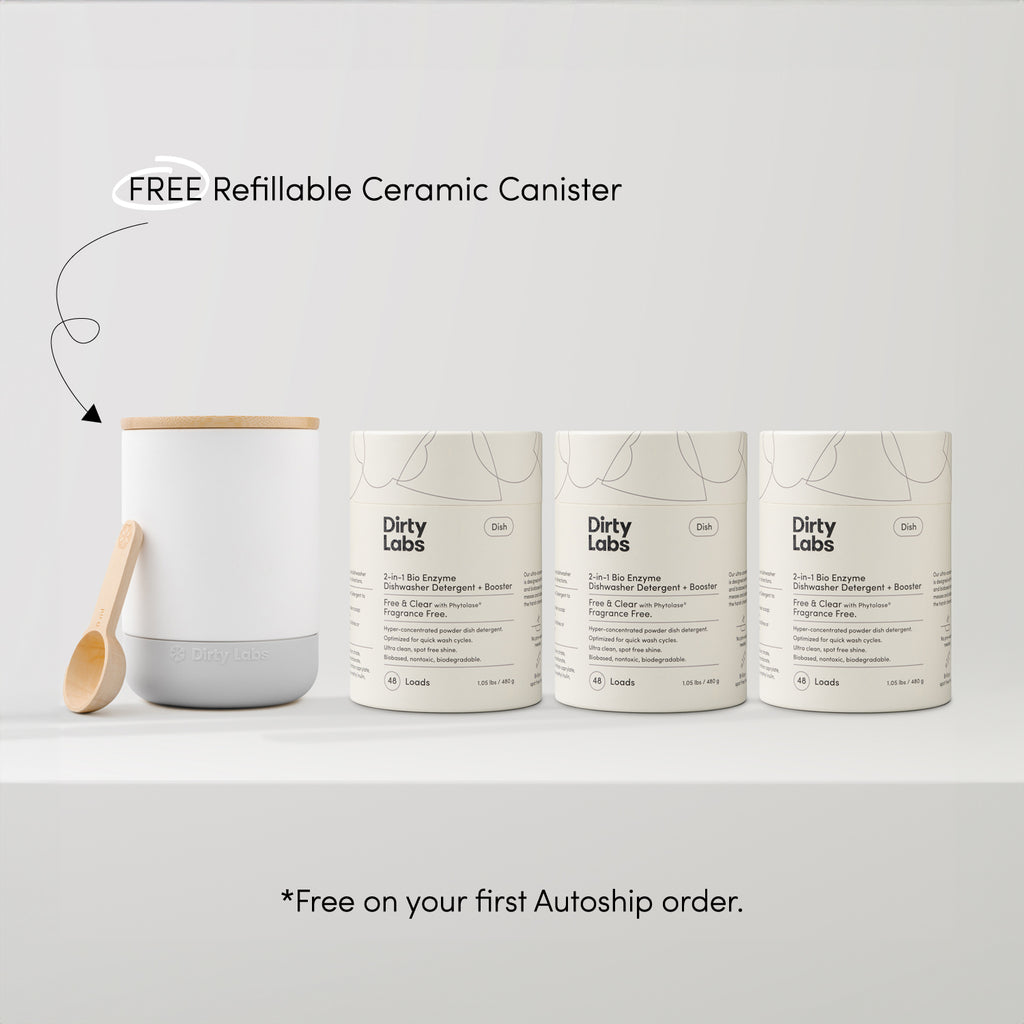 The Dish Trio Bundle Free & Clear + Canister includes a ceramic canister with a wooden lid and spoon next to three laundry detergent refill packs featuring a biodegradable formula. FREE Refillable Ceramic Canister—Free on your first Autoship order.*.