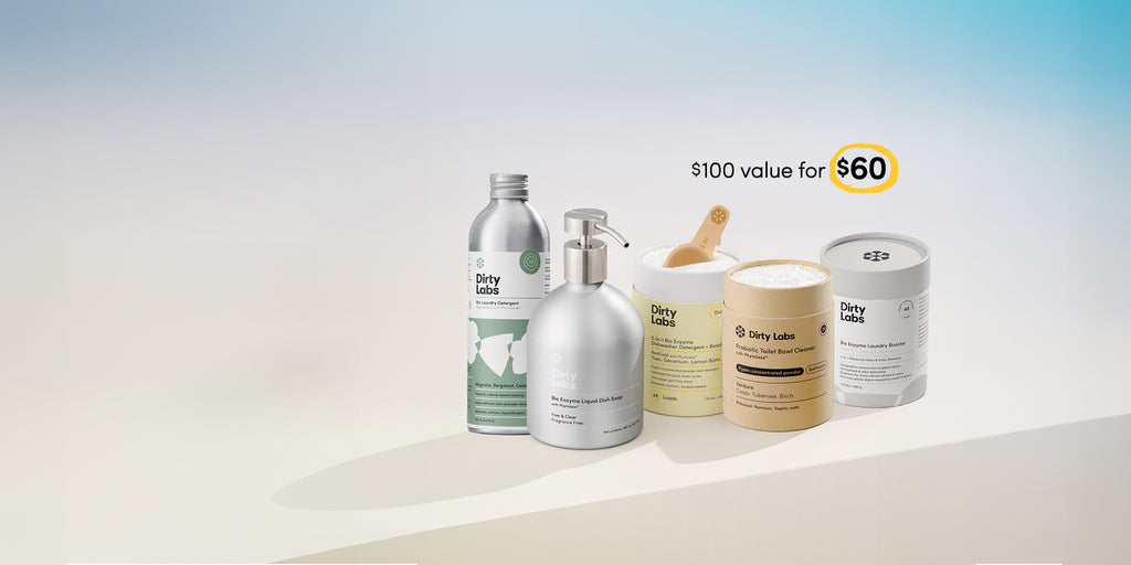 Collection of Dirty Labs cleaning products including 32 load signature detergent, bio enzyme liquid dish soap free and clear, aestival dishwasher detergent, probiotic toilet bowl cleaner, and bio enzyme laundry booster on a light background with promotional text: $100 value for $60