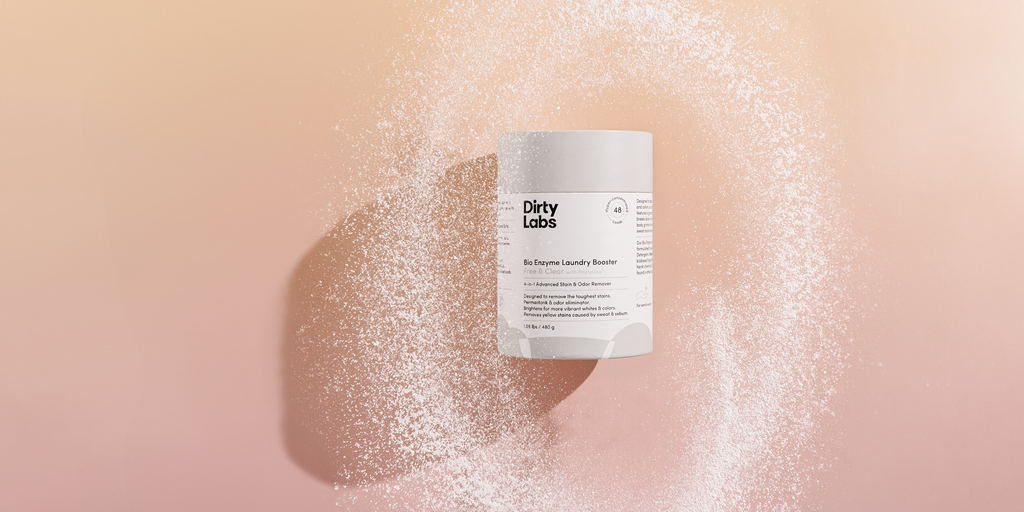 Dirty Labs Booster canister with powder swirling around against light orange backdrop.