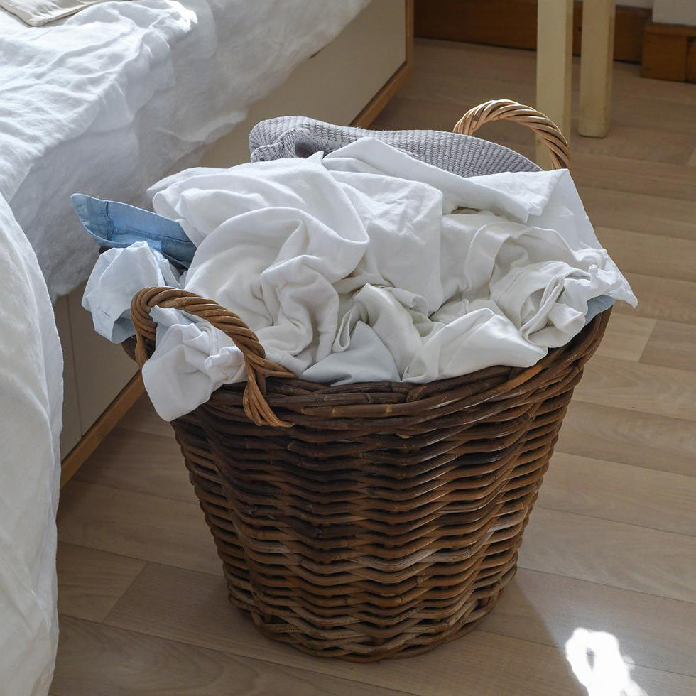 Close up shot of a wicker basket of laundry in a room with sunlight.