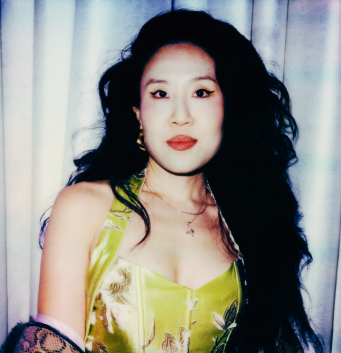 Fashion designer Kim Shui looking at camera in yellow dress with flash.