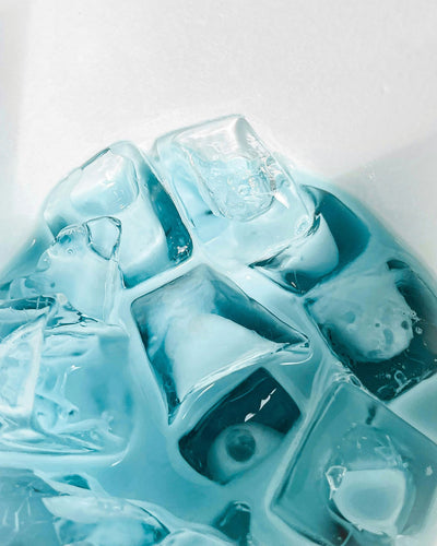 Close-up of laundry pods in a blue liquid on a white background