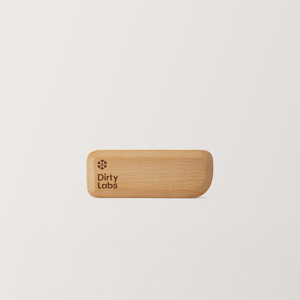 Wooden scraper with 'Dirty Labs' branding on a light grey background