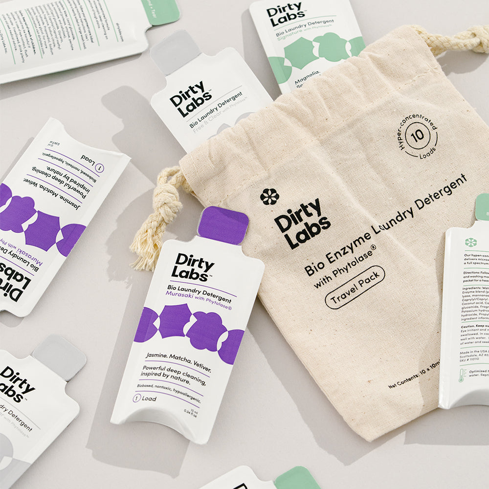 Dirty Labs single dose travel pack detergents and cloth bag spilled on table against light grey background showcasing the 10 pack travel pack product.
